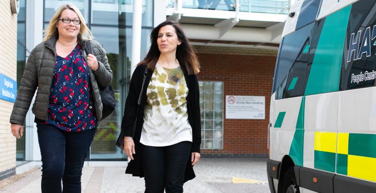 Two women walking next to an ambulance