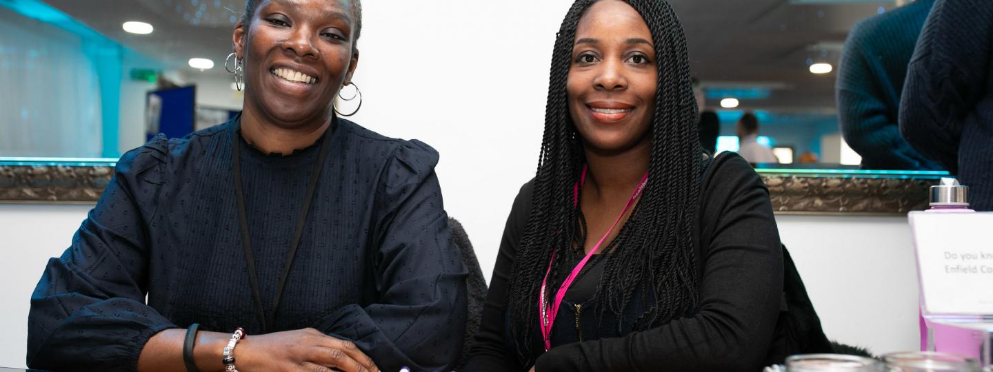 two female staff members sitting behind a desk full of stationary